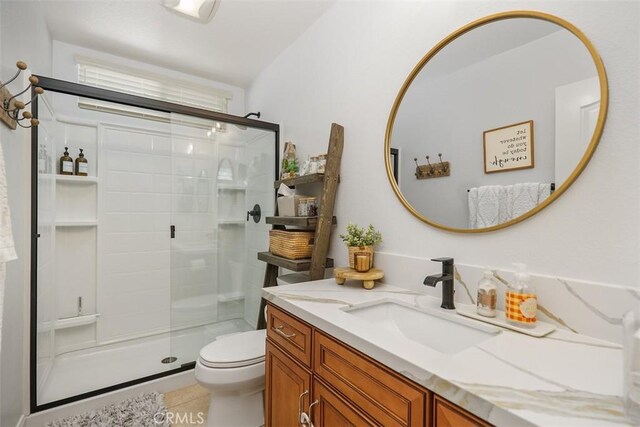 bathroom with toilet, a shower with door, vanity, and tile patterned flooring