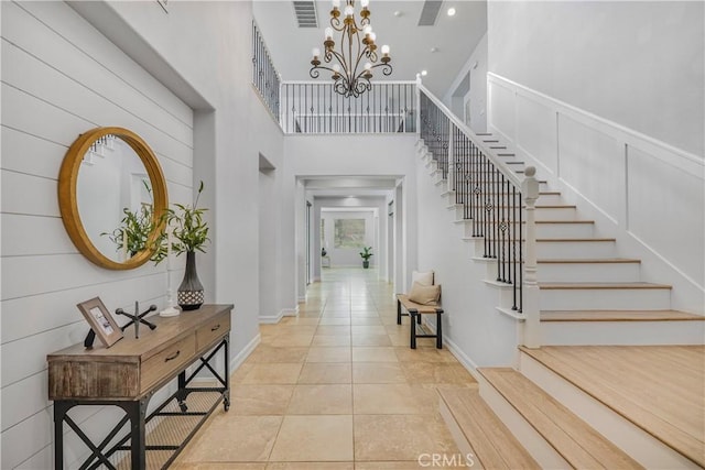 foyer featuring a towering ceiling, light tile patterned floors, and an inviting chandelier