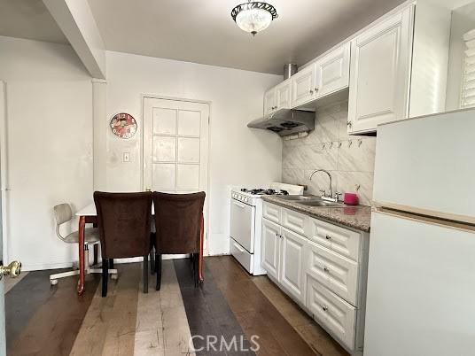 kitchen featuring white cabinets, dark wood-type flooring, and white appliances