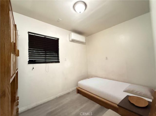 bedroom with a wall mounted AC and light hardwood / wood-style floors