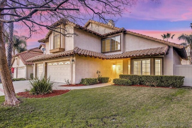 mediterranean / spanish house with a garage and a lawn