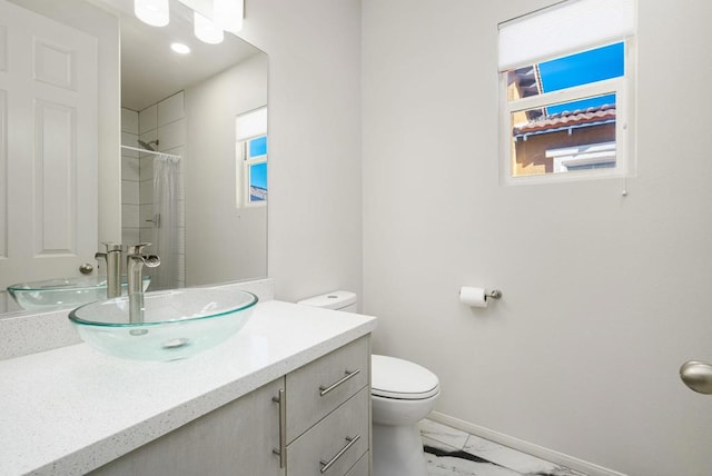 bathroom featuring toilet, vanity, and a shower with curtain