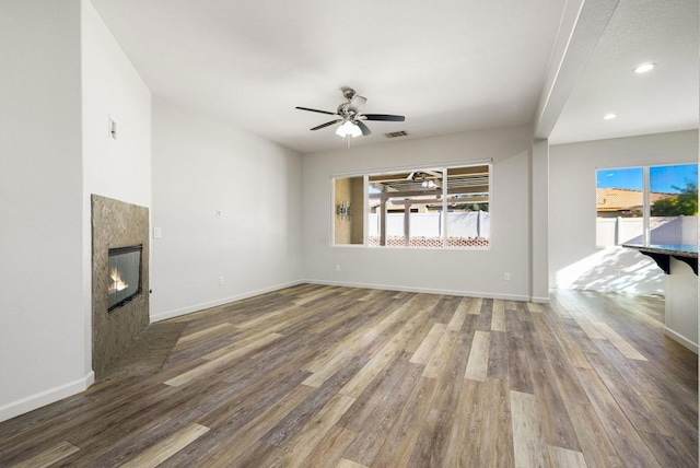 unfurnished living room with ceiling fan, hardwood / wood-style flooring, and a fireplace