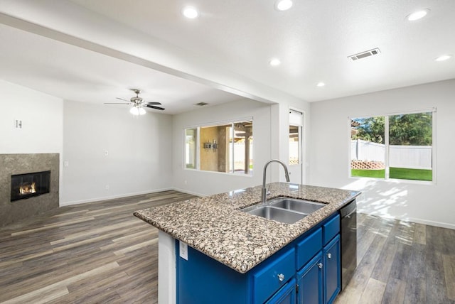 kitchen featuring dark hardwood / wood-style floors, sink, a kitchen island with sink, blue cabinets, and dishwashing machine