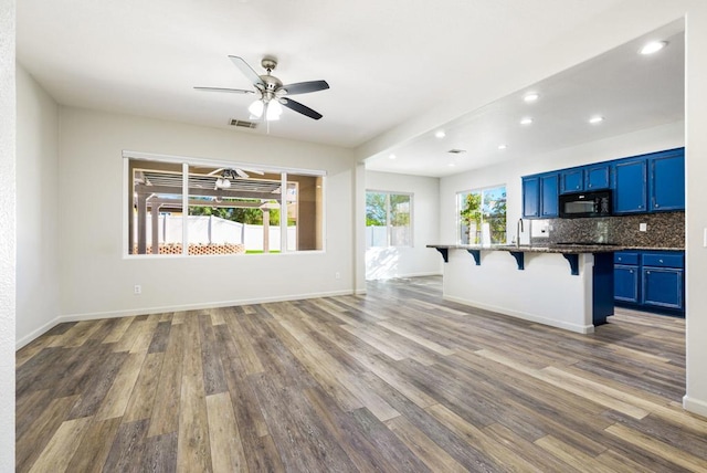 kitchen with a kitchen bar, backsplash, blue cabinetry, and hardwood / wood-style floors