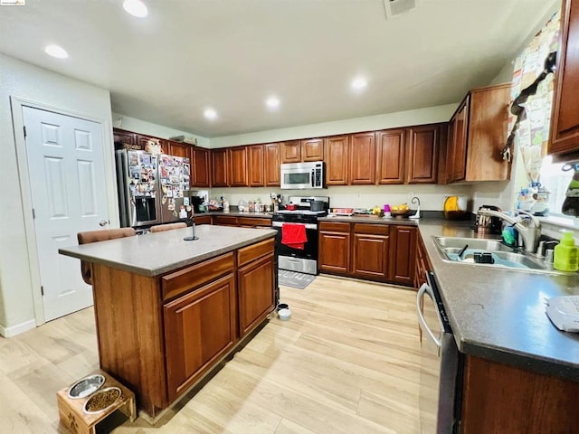 kitchen with sink, appliances with stainless steel finishes, light hardwood / wood-style flooring, and a kitchen island with sink