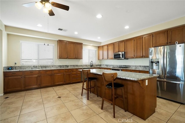 kitchen featuring a center island, stainless steel appliances, a breakfast bar area, and light tile patterned flooring