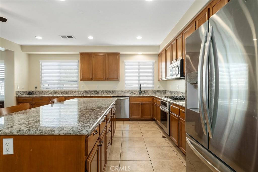 kitchen featuring light stone countertops, stainless steel appliances, a kitchen island, and sink