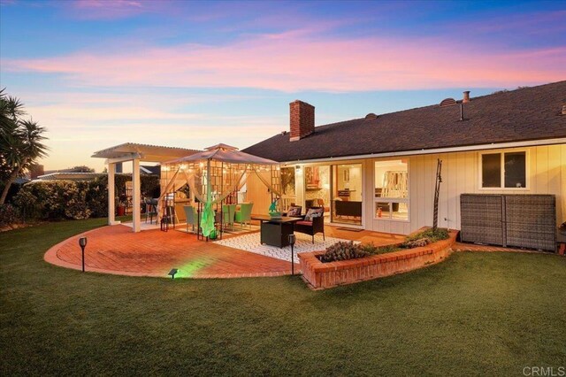 back house at dusk featuring an outdoor hangout area, a pergola, a patio area, and a lawn