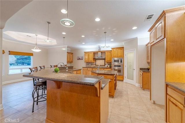 kitchen featuring appliances with stainless steel finishes, a kitchen bar, hanging light fixtures, and a large island