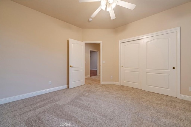 unfurnished bedroom featuring ceiling fan, a closet, and light carpet