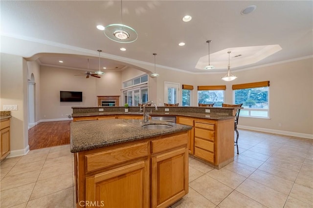 kitchen featuring ceiling fan, hanging light fixtures, crown molding, a large island with sink, and sink