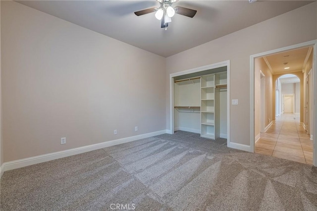 unfurnished bedroom featuring ceiling fan, a closet, and light colored carpet