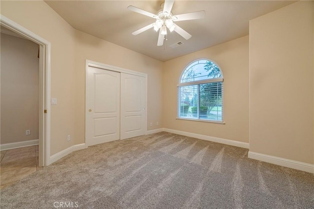 unfurnished bedroom with ceiling fan, a closet, and carpet floors