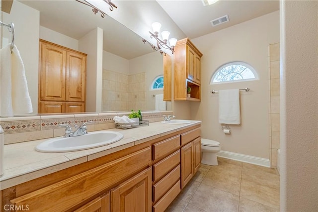 bathroom with tile patterned floors, vanity, tasteful backsplash, toilet, and walk in shower