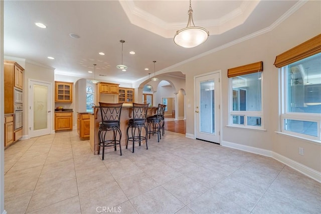 kitchen featuring pendant lighting, a tray ceiling, crown molding, and oven