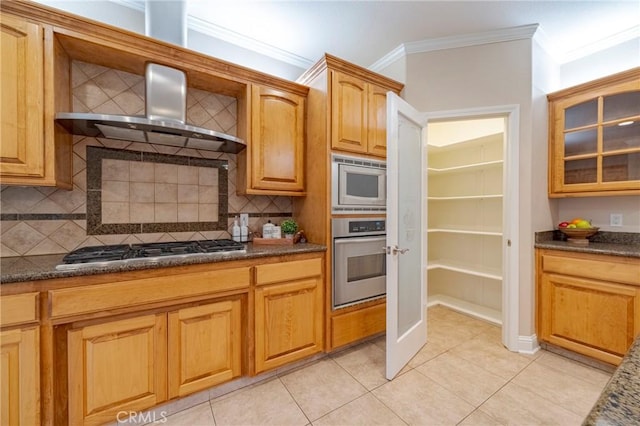 kitchen featuring light tile patterned floors, stainless steel appliances, dark stone counters, and wall chimney range hood