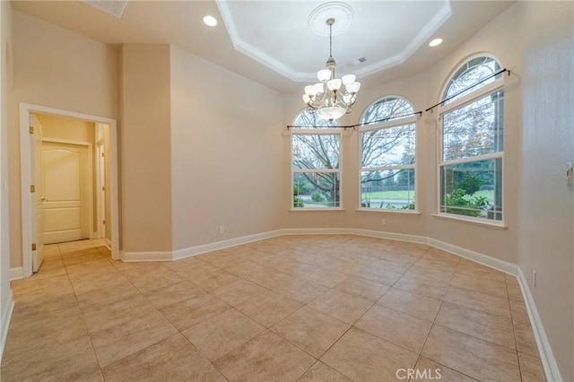 tiled spare room featuring a tray ceiling and a chandelier