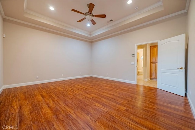 unfurnished room with a raised ceiling, ceiling fan, ornamental molding, and light hardwood / wood-style floors