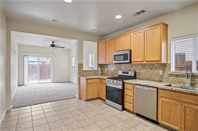 kitchen with ceiling fan, backsplash, sink, stainless steel appliances, and light carpet