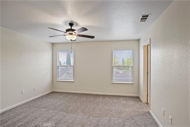 carpeted empty room featuring a textured ceiling, ceiling fan, and a healthy amount of sunlight