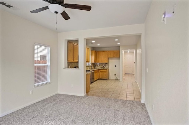 unfurnished living room featuring ceiling fan, light colored carpet, and sink