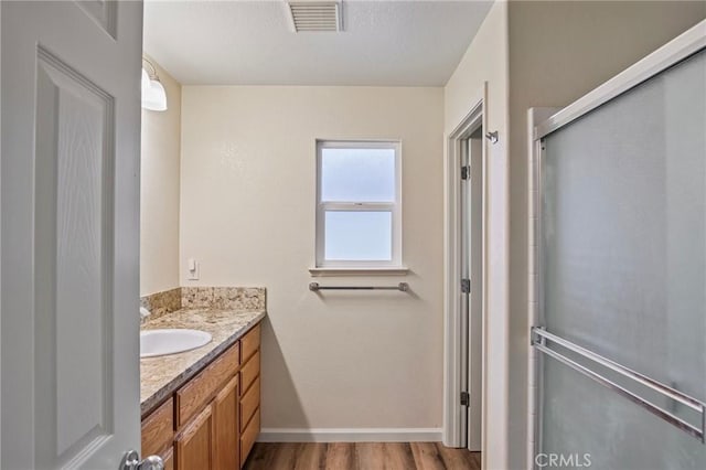 bathroom featuring walk in shower, vanity, and hardwood / wood-style floors