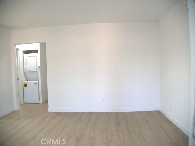 spare room featuring light hardwood / wood-style floors and stacked washer / dryer