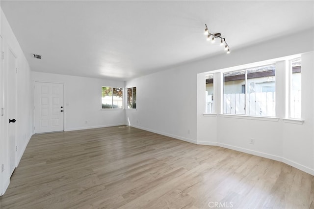 empty room featuring track lighting and light hardwood / wood-style floors