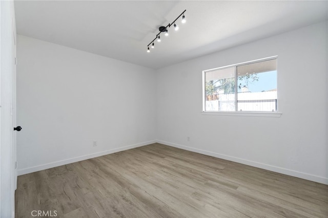 unfurnished room featuring rail lighting and light hardwood / wood-style floors