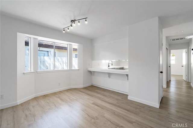 interior space with a breakfast bar, kitchen peninsula, light hardwood / wood-style flooring, and track lighting