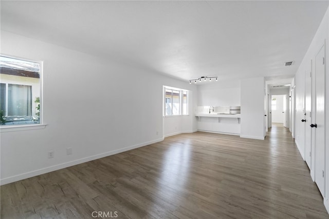 unfurnished living room featuring dark wood-type flooring, sink, and track lighting