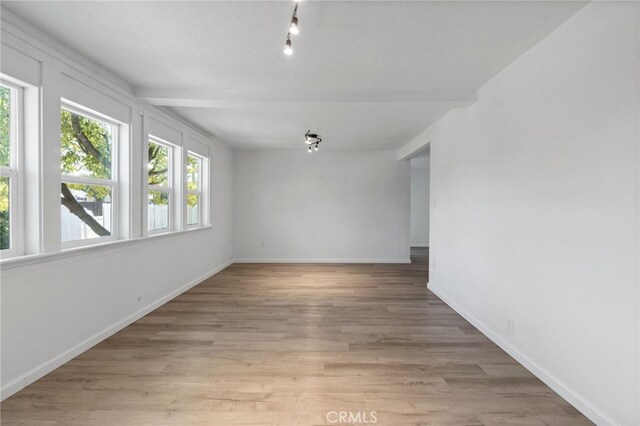 empty room featuring light hardwood / wood-style flooring and beam ceiling