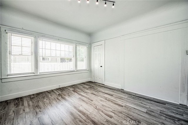 unfurnished bedroom featuring light wood-type flooring, a closet, and multiple windows