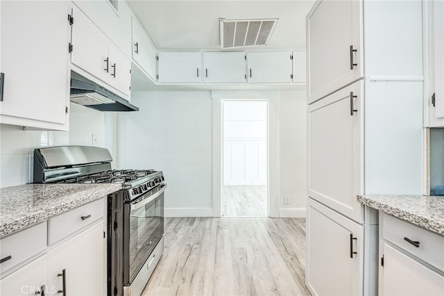 kitchen with white cabinets, light stone countertops, stainless steel range with gas stovetop, and light hardwood / wood-style floors