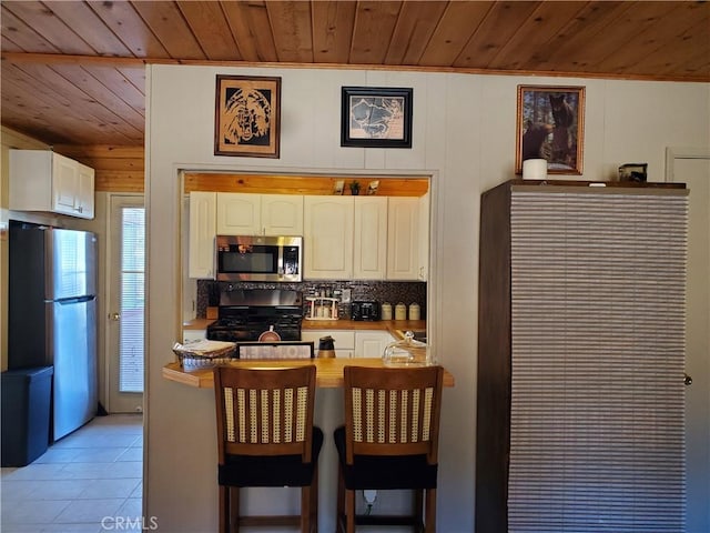 kitchen featuring white cabinets, appliances with stainless steel finishes, butcher block counters, wooden ceiling, and light tile patterned floors