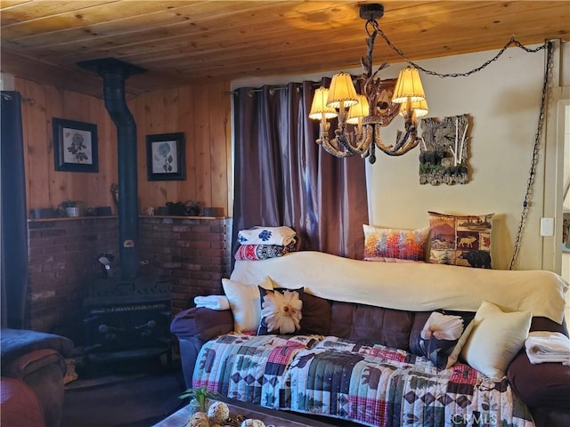 bedroom featuring wood ceiling, a wood stove, wood walls, and a notable chandelier