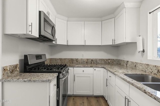 kitchen featuring sink, appliances with stainless steel finishes, dark hardwood / wood-style floors, light stone countertops, and white cabinets