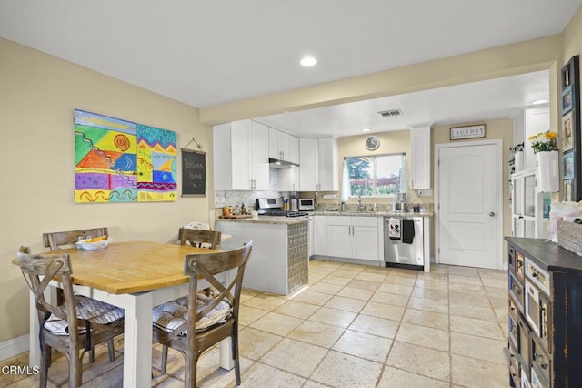 kitchen with sink, white cabinetry, stainless steel appliances, light stone counters, and decorative backsplash