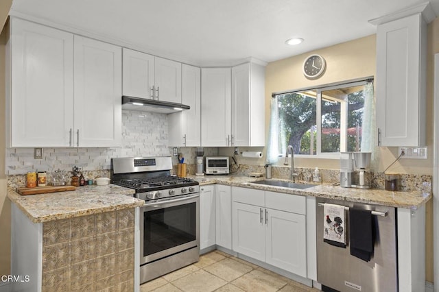 kitchen with white cabinetry, appliances with stainless steel finishes, sink, and light stone counters