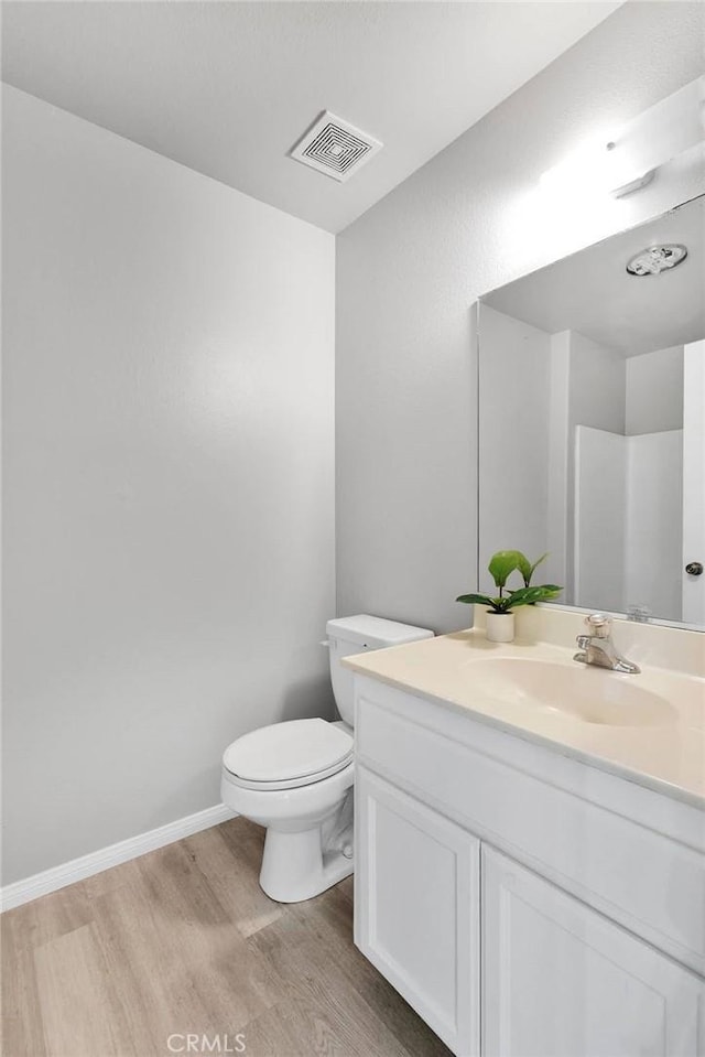 bathroom featuring toilet, walk in shower, wood-type flooring, and vanity