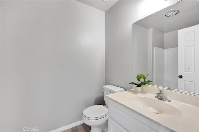 bathroom with toilet, vanity, and wood-type flooring