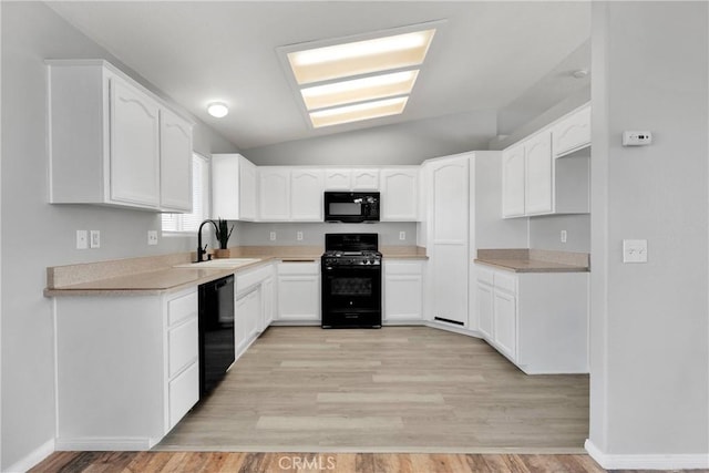 kitchen with lofted ceiling, light hardwood / wood-style floors, black appliances, sink, and white cabinetry