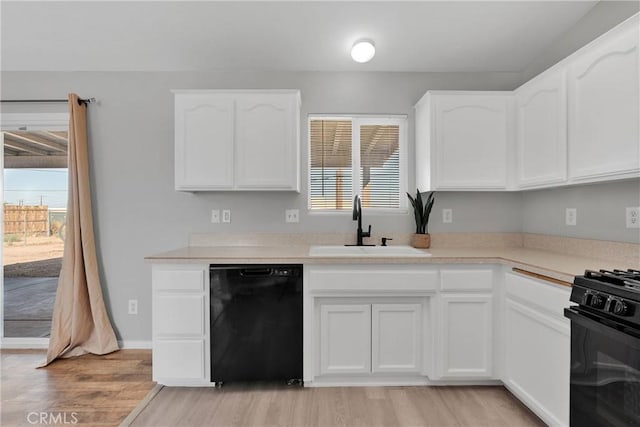 kitchen with sink, white cabinetry, black appliances, and light wood-type flooring