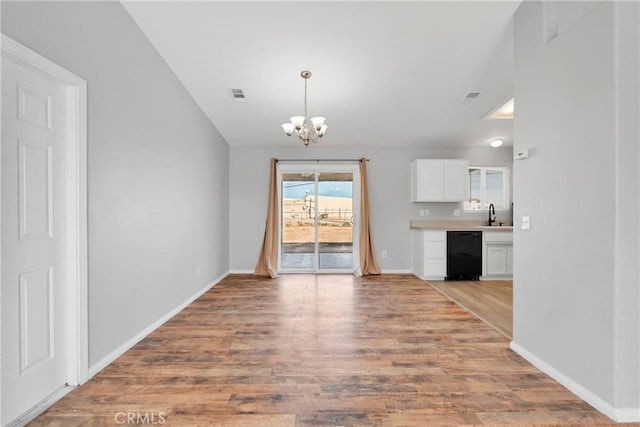 unfurnished dining area with light wood-type flooring, sink, and a notable chandelier