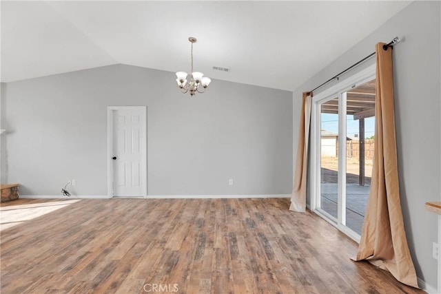 unfurnished room with hardwood / wood-style flooring, lofted ceiling, and an inviting chandelier