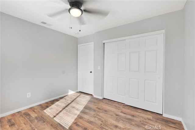 unfurnished bedroom with ceiling fan, wood-type flooring, and a closet