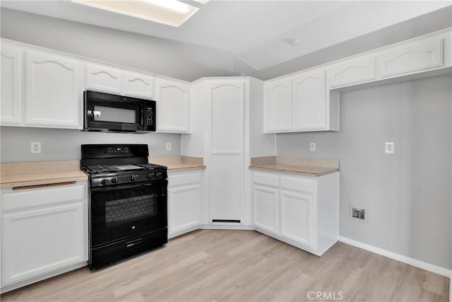 kitchen featuring white cabinetry, black appliances, lofted ceiling, and light hardwood / wood-style flooring