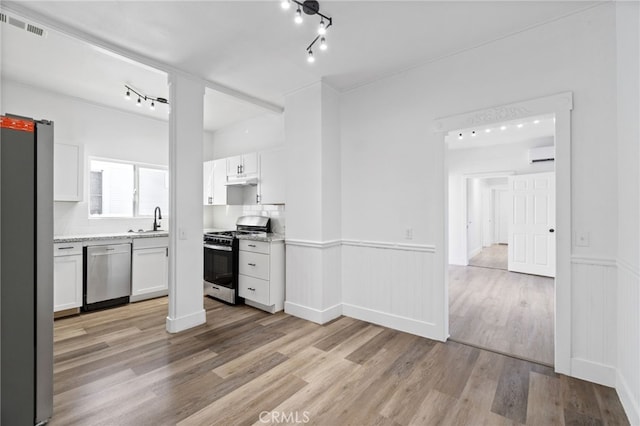 kitchen with light hardwood / wood-style floors, white cabinetry, appliances with stainless steel finishes, and tasteful backsplash