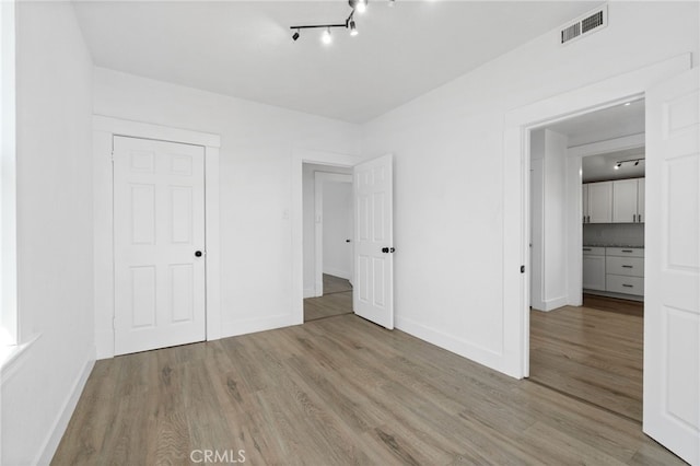 unfurnished bedroom with light wood-type flooring and a closet